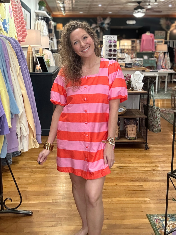 Woman wearing a red and pink striped dress in a store setting