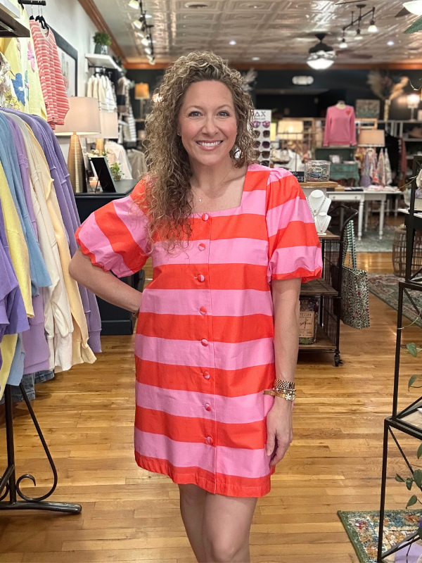 Woman wearing a red and pink striped dress in a store setting