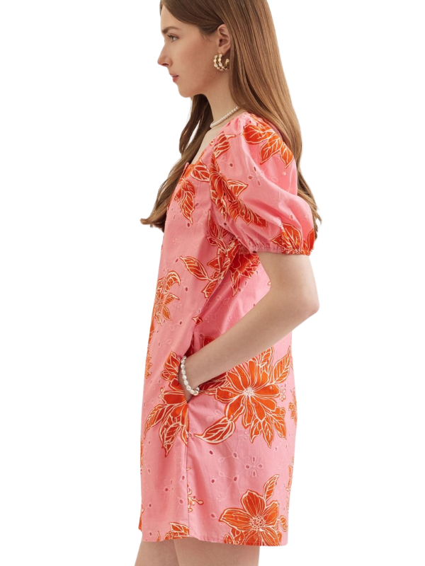Woman wearing a pink dress with orange floral pattern on a white background