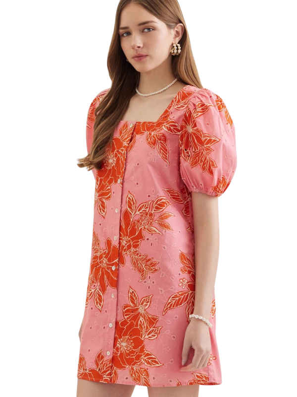 Woman wearing a pink dress with orange floral pattern on a white background