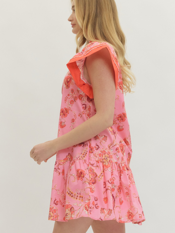 Woman wearing a pink floral dress with orange trim on a plain background