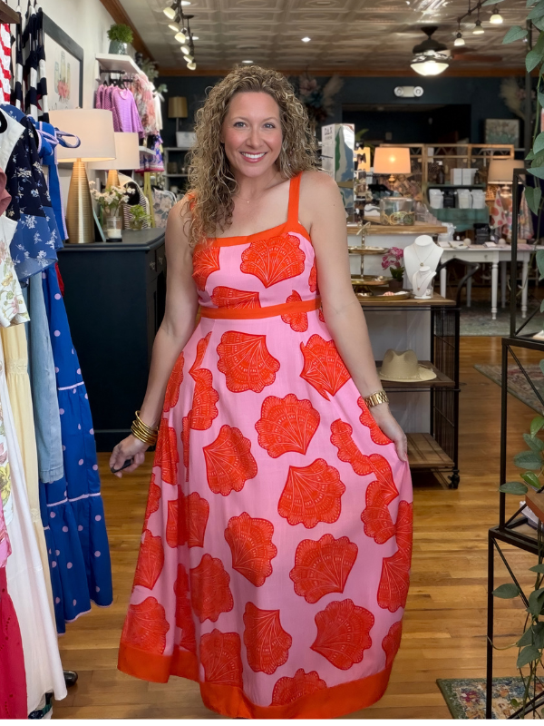 Woman wearing a pink and red floral dress in a store setting
