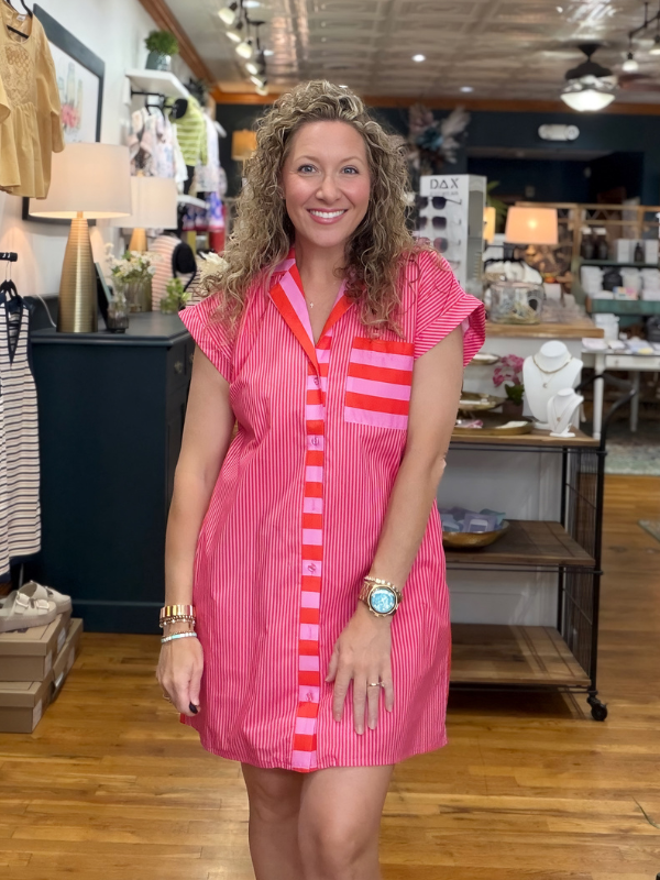 Woman wearing a pink dress with red stripes in a store setting