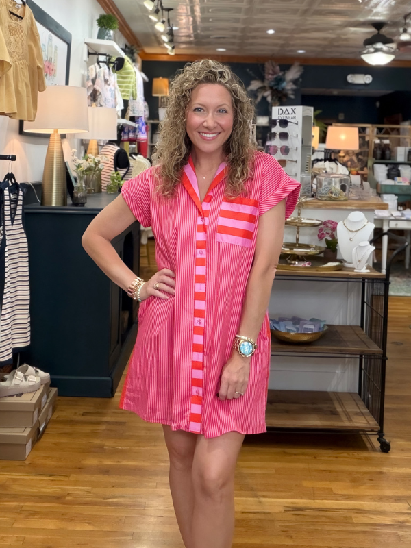 Woman wearing a pink dress with red stripes in a store setting