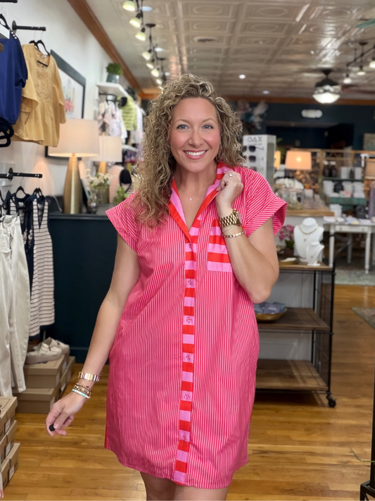 Woman wearing a pink dress with red accents in a store setting