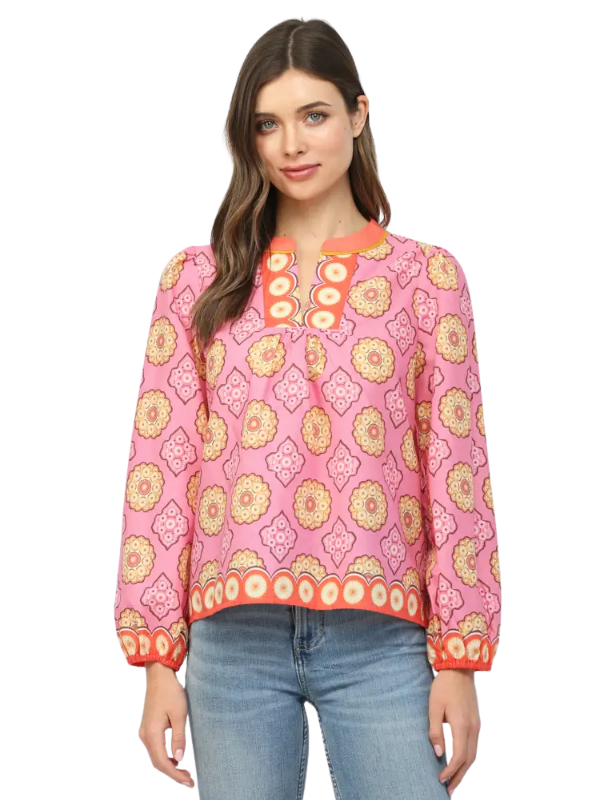 Woman wearing a pink patterned blouse with blue jeans on a white background