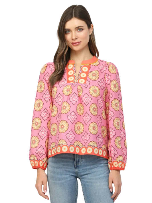 Woman wearing a pink patterned blouse with blue jeans on a white background
