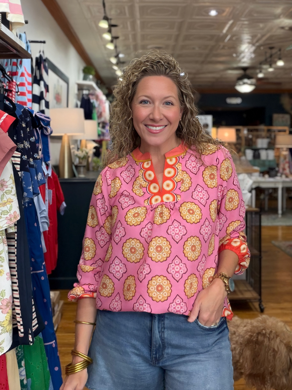 Woman wearing a pink floral blouse in a store setting