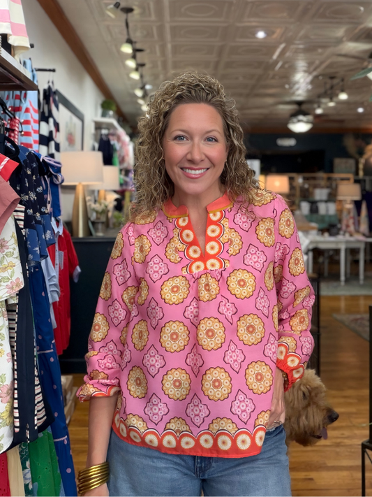 Woman wearing a pink patterned blouse in a store setting