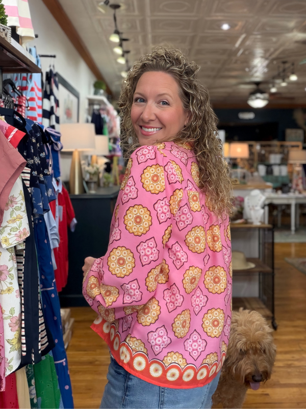 Woman wearing a pink floral patterned shirt in a store setting with a dog.
