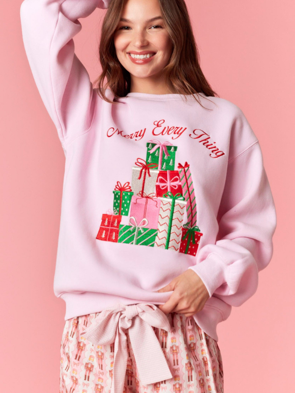 Woman wearing a pink sweatshirt with Christmas gift design and text on a pink background