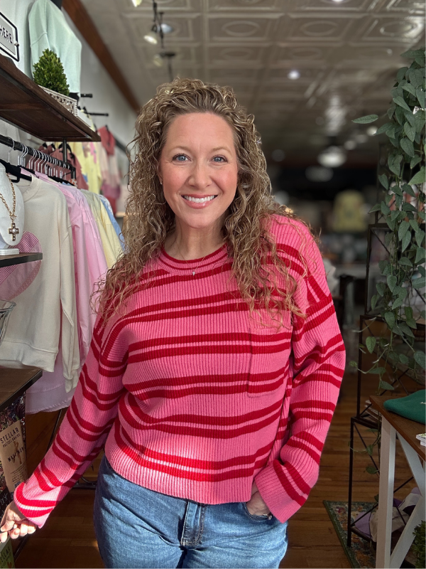 Woman wearing a pink striped sweater in a store setting