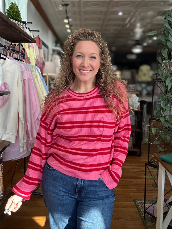 Woman wearing a pink striped sweater in a store setting