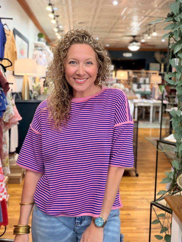 Woman wearing a purple and pink striped shirt in a store setting