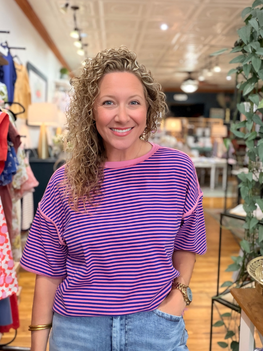 Woman wearing a purple and pink striped shirt in a store setting