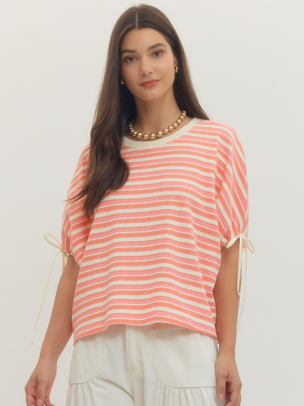 Woman wearing a pink and white striped top with a plain background