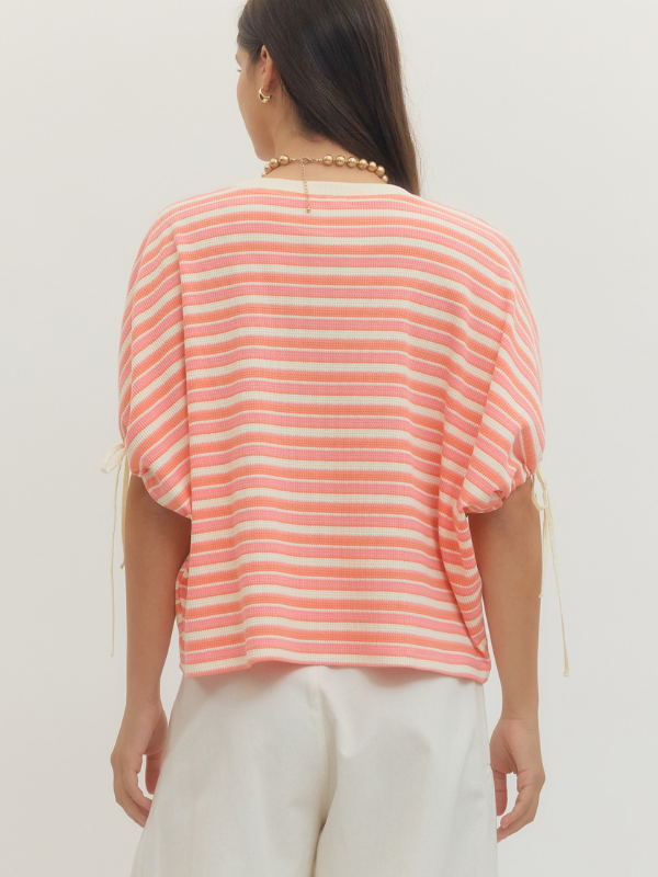 Woman wearing a pink and white striped top against a plain background