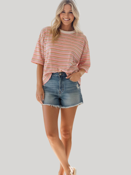 Woman wearing a striped shirt and denim shorts on a plain background