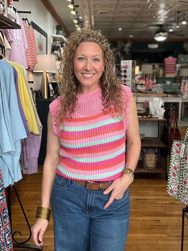 Woman wearing a colorful striped sleeveless top in a clothing store.