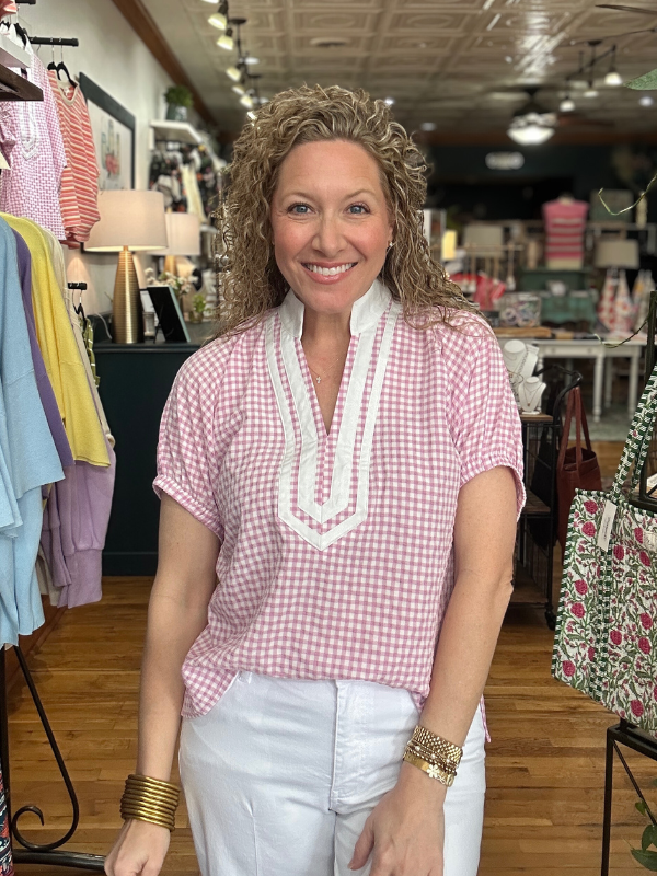 Woman wearing a pink checkered shirt with white trim in a store setting