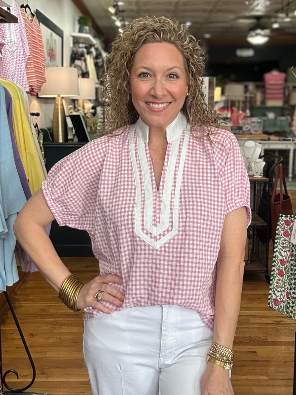 Woman wearing a pink checkered shirt with white trim in a store setting