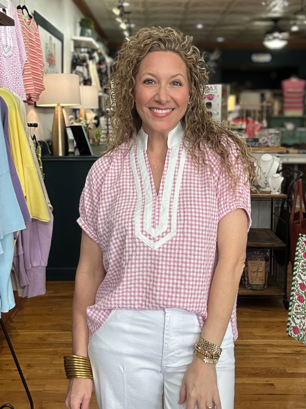 Woman wearing a pink checkered top with white trim in a store setting