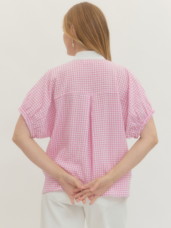 Person wearing a pink checkered shirt against a plain background
