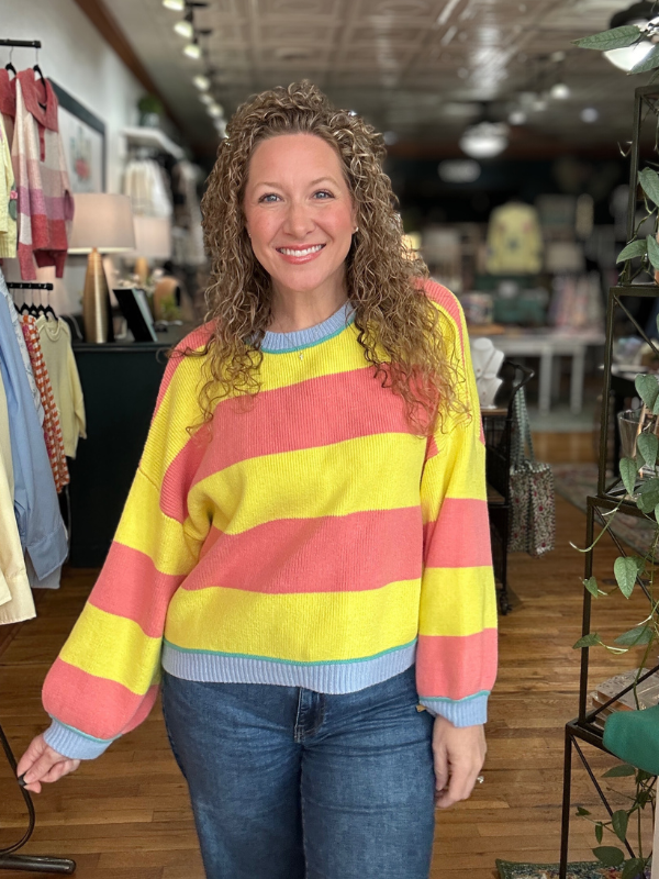 Woman wearing a colorful striped sweater in a store setting