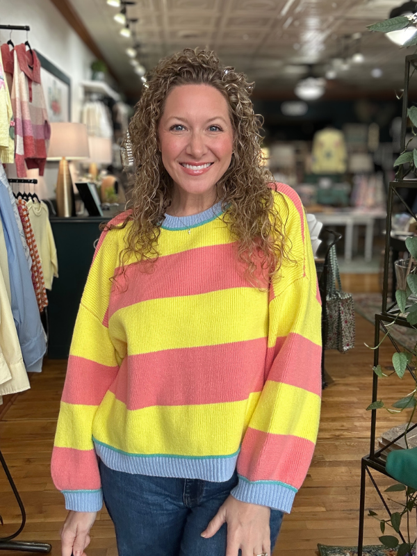 Woman wearing a colorful striped sweater in a store setting