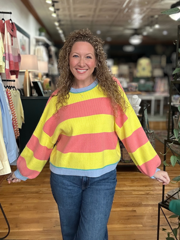 Woman wearing a colorful striped sweater in a store setting
