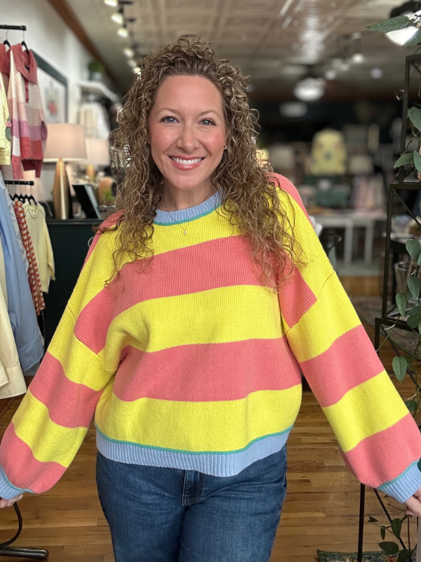 Woman wearing a colorful striped sweater in a store setting