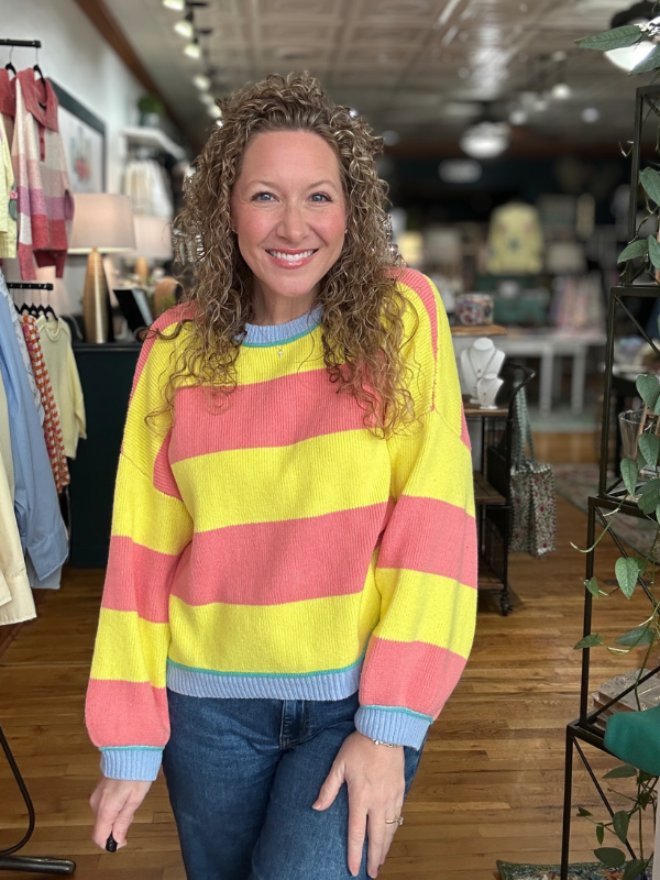Woman wearing a colorful striped sweater in a store setting