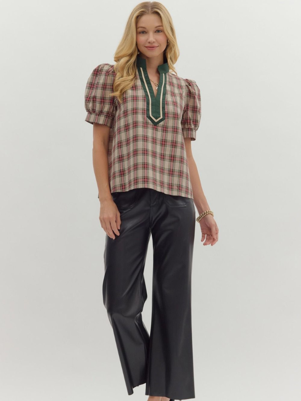 Woman wearing a plaid top with green accents and black pants on a white background