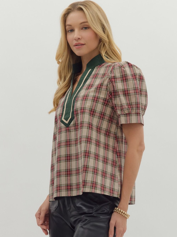 Woman wearing a plaid shirt with green trim on a plain background