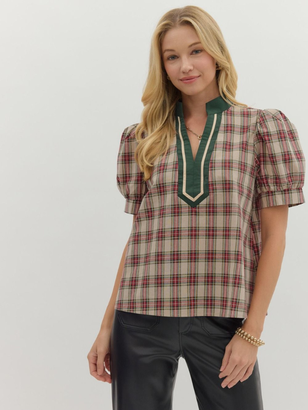 Woman wearing a plaid blouse with green accents on a white background