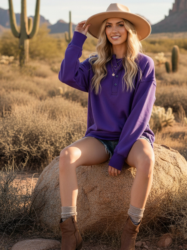 Woman in a purple shirt and cowboy hat sitting on a rock in a desert landscape