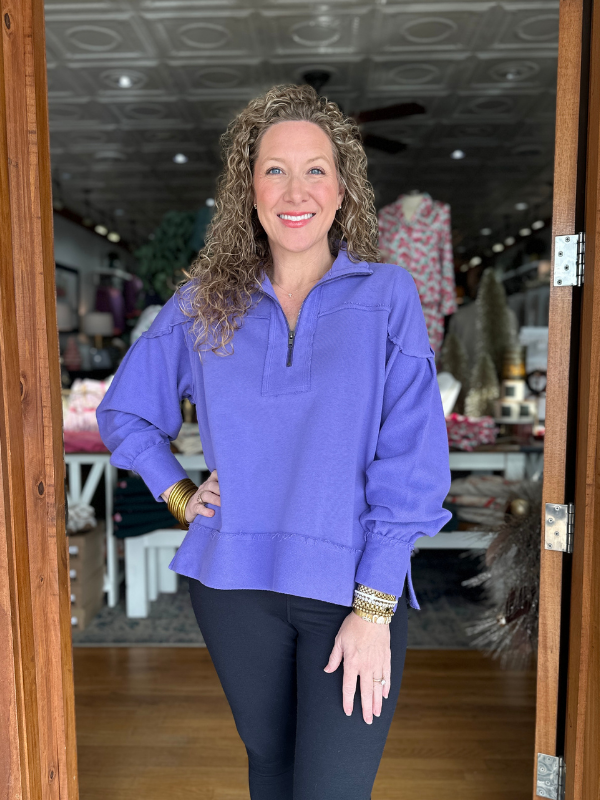 Woman wearing a purple pullover in a store setting