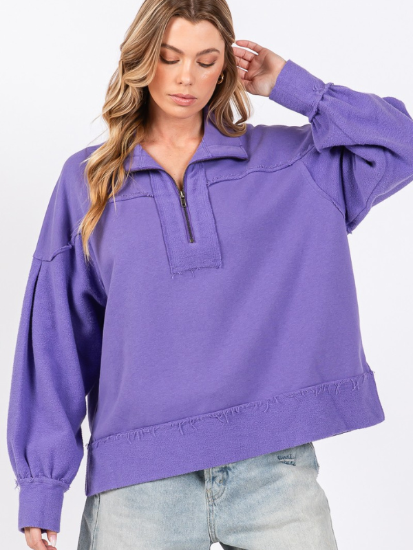 Woman wearing a purple pullover with a quarter zip on a white background