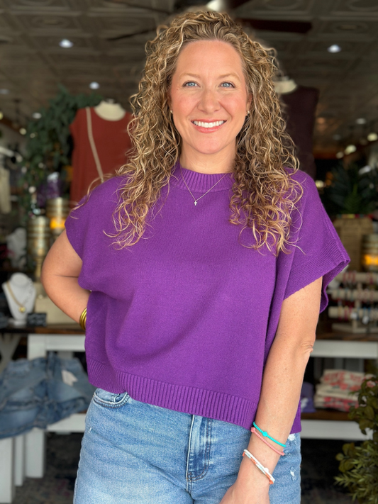 Woman wearing a purple sweater and blue jeans in an indoor setting