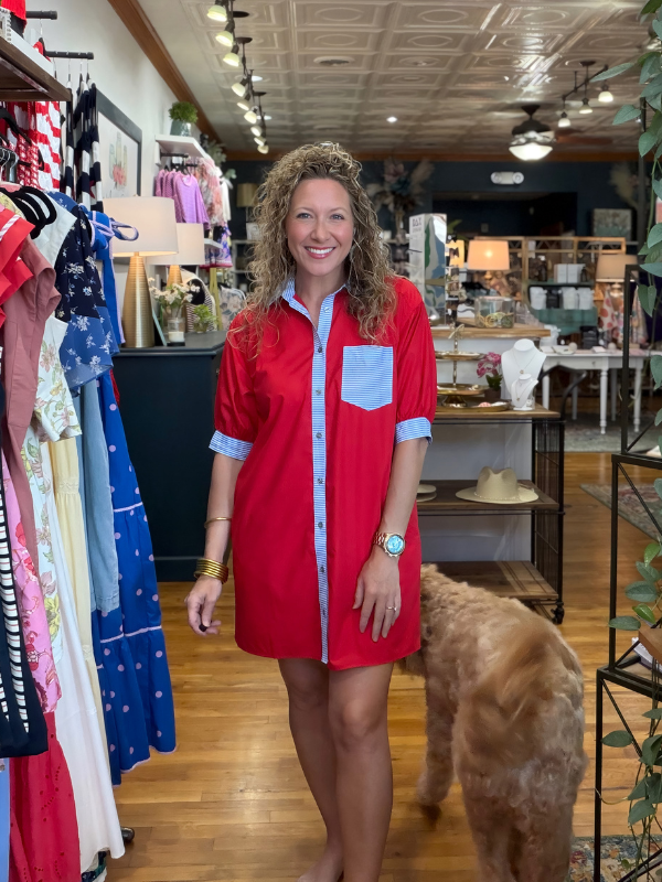 Woman in a red dress standing in a clothing store with a dog.