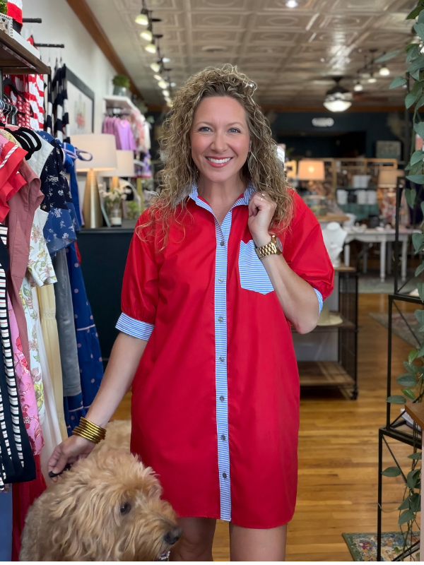 Woman in a red dress standing in a store with a dog by her side