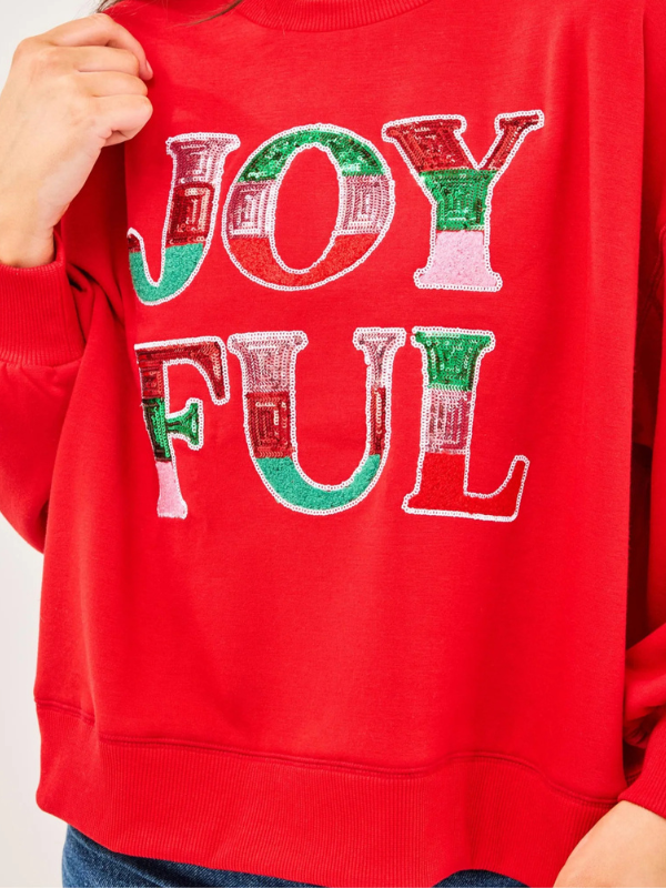 Red sweatshirt with 'JOYFUL' text in sequins on a plain background