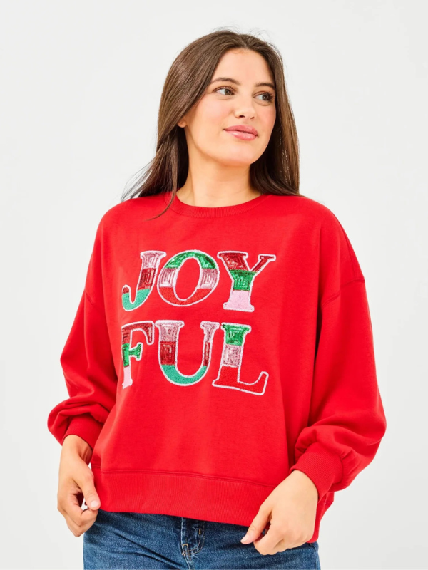 Person wearing a red sweatshirt with 'JOYFUL' text on a plain background