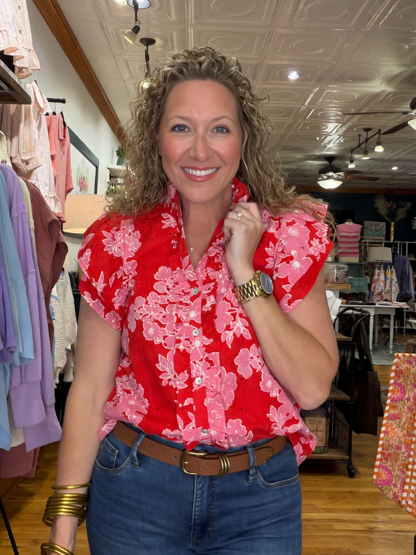 Woman wearing a red floral blouse in a clothing store