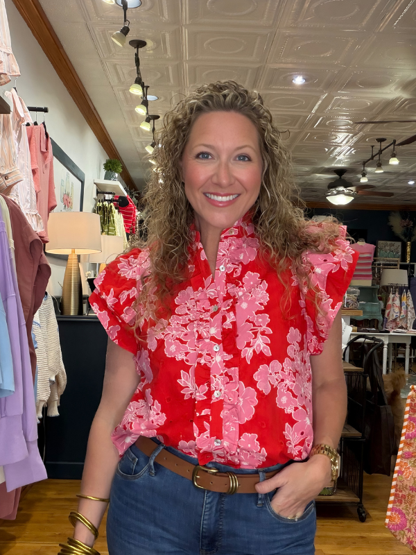 Woman wearing a red floral blouse in a store setting