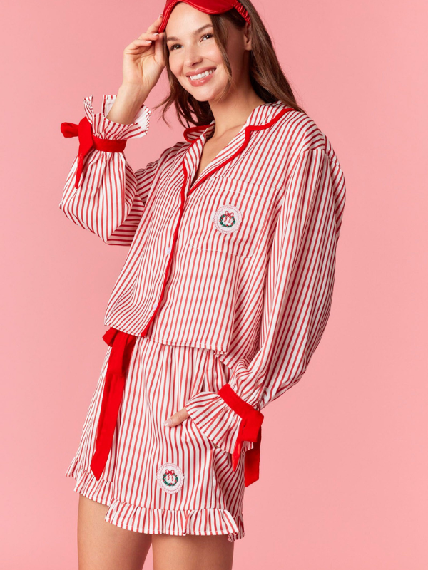Woman wearing a red and white striped pajama set with a pink background