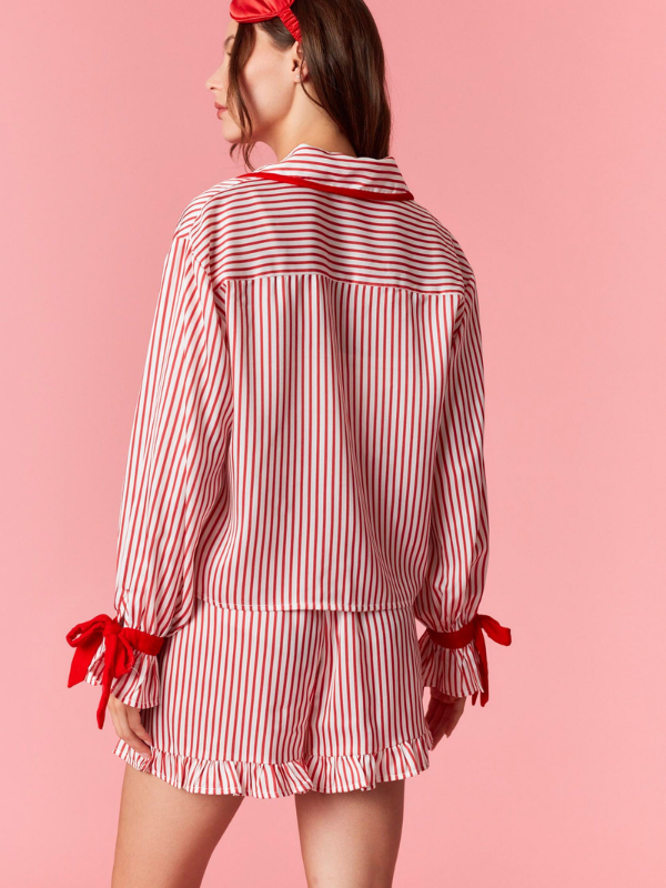 Woman wearing a red and white striped outfit with ruffled details on a pink background