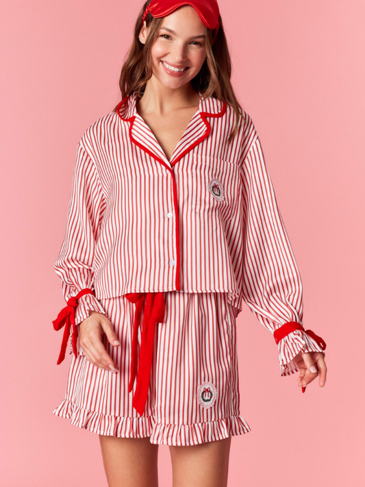 Woman wearing a red and white striped pajama set with a matching headband on a pink background