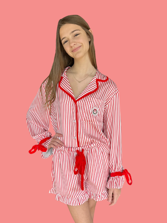 Woman wearing a red and white striped outfit with a bow on a pink background