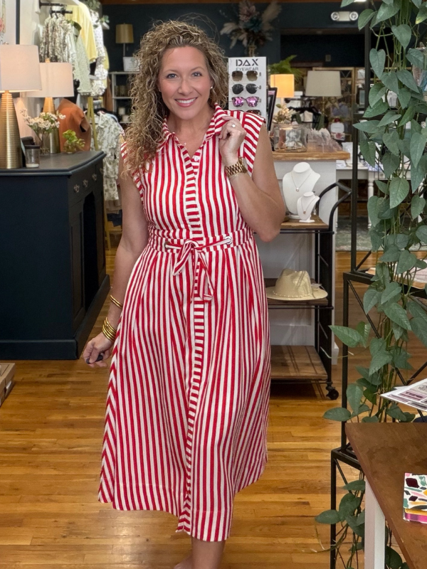 Woman in a red and white striped dress holding a phone in a store setting.